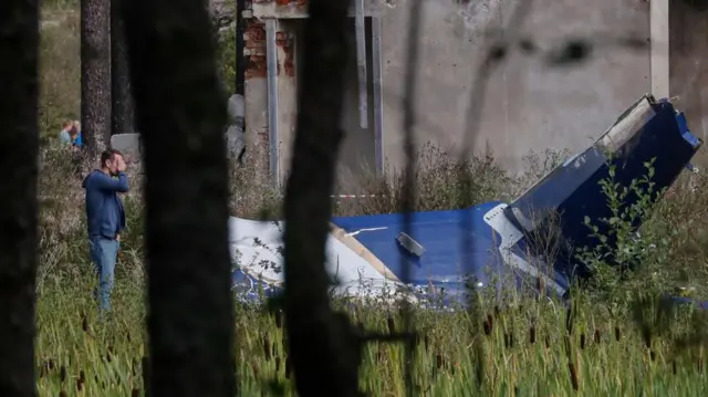 A man stands by debris of a crashed plane