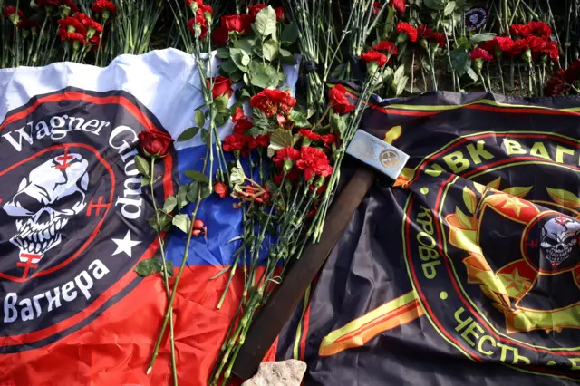 Flags and a sledgehammer with the Wagner logo among flowers are among the tributes that have been laid