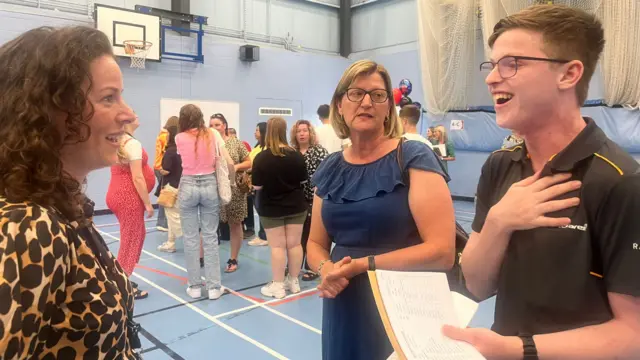 Student Kieran (right) smiling and holidng his GCSE results