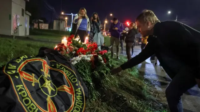 A man puts flowers at a makeshift memorial near former PMC Wagner Centre in Saint Petersburg, Russia August 24, 2023