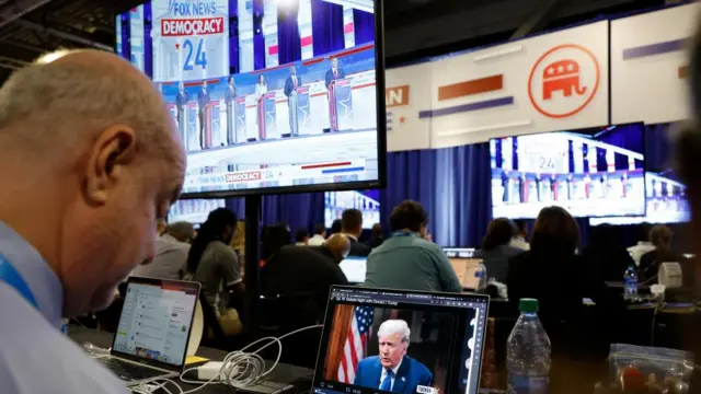 A reporter watches former President Donald Trump's online interview with Tucker Carlson in the media filing center