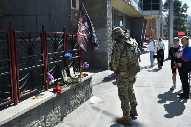 A member of Wagner pays tribute to Prigozhin in front of the PMC Wagner office in Novosibirsk