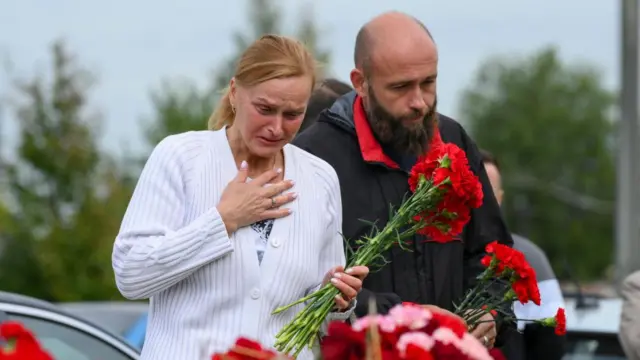 A female and a male mourner leave flowers at a makeshift shrine for Yevgeny Prigozhin