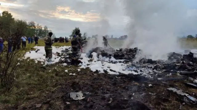 Firefighters work amid aircraft wreckage at an accident scene following the crash of a private jet in the Tver region, Russia