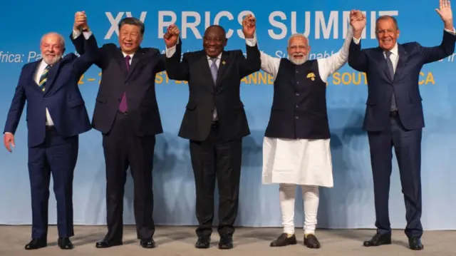 From left: Brazil's President Luiz Inacio Lula da Silva, China's President Xi Jinping, South African President Cyril Ramaphosa, Indian Prime Minister Narendra Modi and Russia's Foreign Minister Sergei Lavrov raise their arms as they pose for a group photograph, at the Brics summit in Johannesburg - 23 August 2023