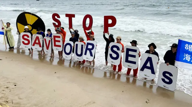 Activists, holding signs which read "Stop, save our seas", protest against the water being discharged from Fukushima into the Pacific Ocean