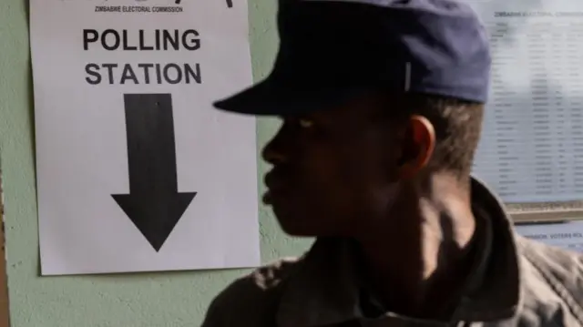 A police officer stands at an entrance controlling a queue at a polling station in Harare, Zimbabwe - 24 August 2023,