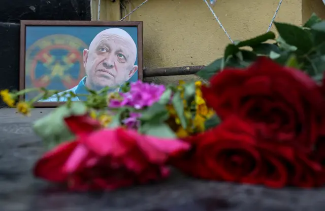 A framed photo of Yevgeny Prigozhin with flowers in the foreground