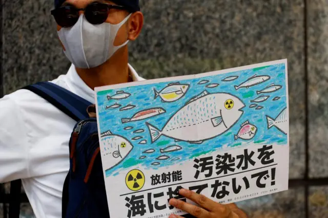 A protester holds a placard with a slogan that reads "No radiation contaminated water into the sea"