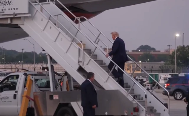 Trump walks up stairs to his plane