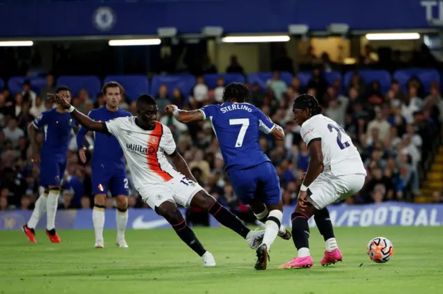 Raheem Sterling shoots between two Luton defenders.