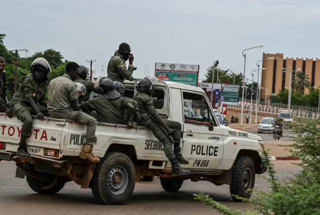 Police officer ride on the back of a pick-up truck as they patrol in Niamey on August 21, 2023.