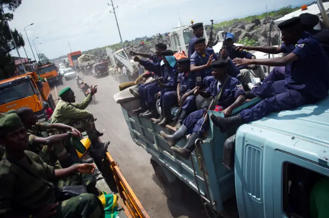 Congoles M23 rebels (L) pass a truck of police officers as they withdraw on December 1, 2012 from the city of Goma in the east of the Democratic Republic of the Congo