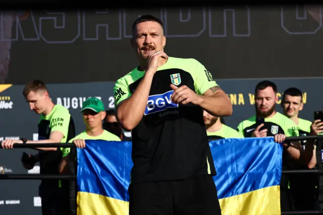 Oleksandr Usyk stands in front of a Ukraine flag