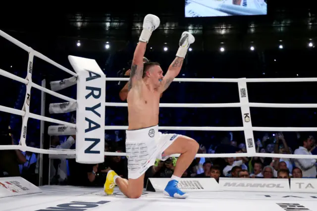 Oleksandr Usyk takes a knee and puts his arms up in the air