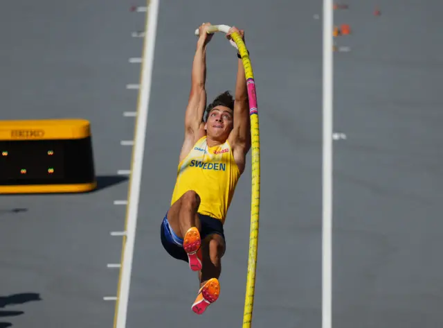 Armand Duplantis springs into the air holding onto the pole