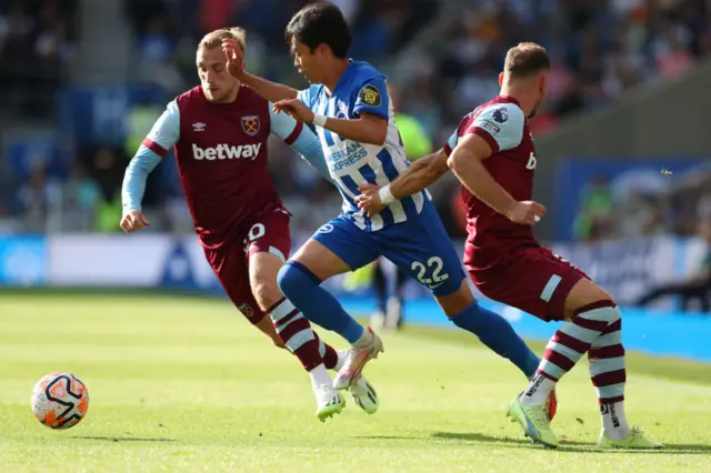 Mitoma is chased by two West Ham defenders.