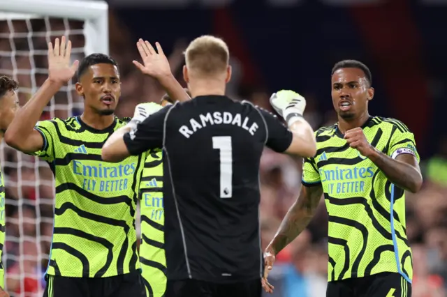 Ramsdale, Gabriel and Saliba celebrate a key save at palace with high fives.