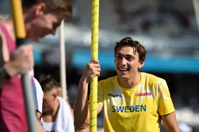 Armand Dupantis laughs with a fellow pole vault competitor