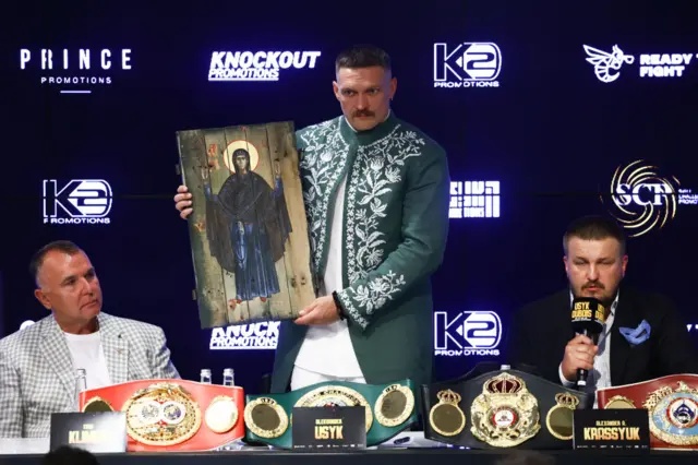 Oleksandr Usyk holds an icon painted on a wooden board