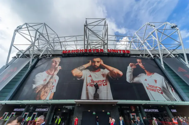 Old Trafford's main facade with the key faces of the men's side on it.