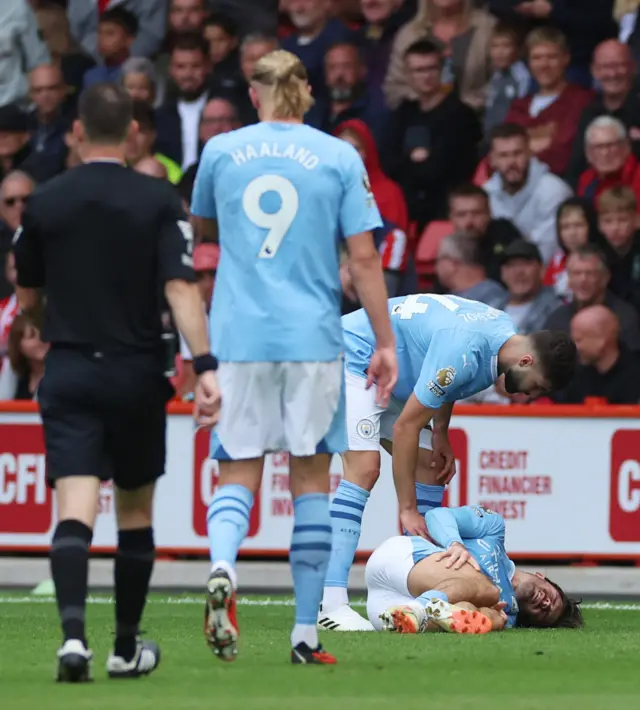 Grealish lies on the turf in pain and is checked on by Gvardiol.