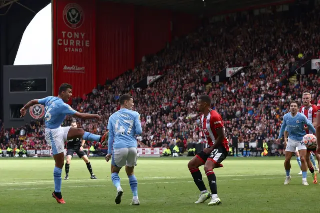 Rodri fires towards goal as defenders look on.