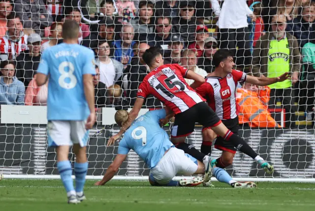 Baldock and Egan flatten Haaland in the box.