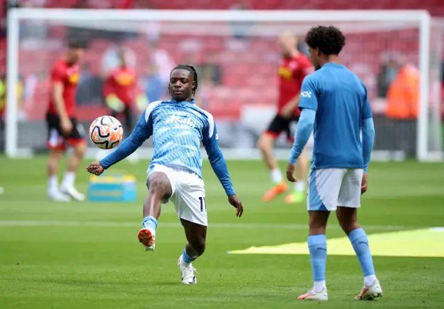 Doku stretches for a ball in the warm up alongside Rico Lewis.