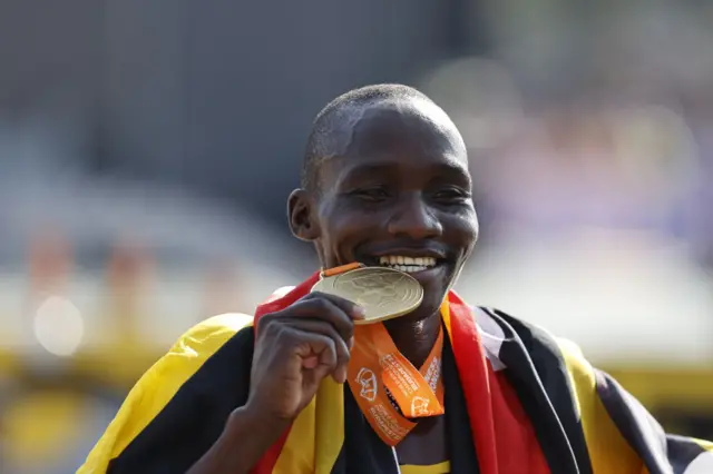 Victor Kiplangat bites his gold medal after winning the men's marathon