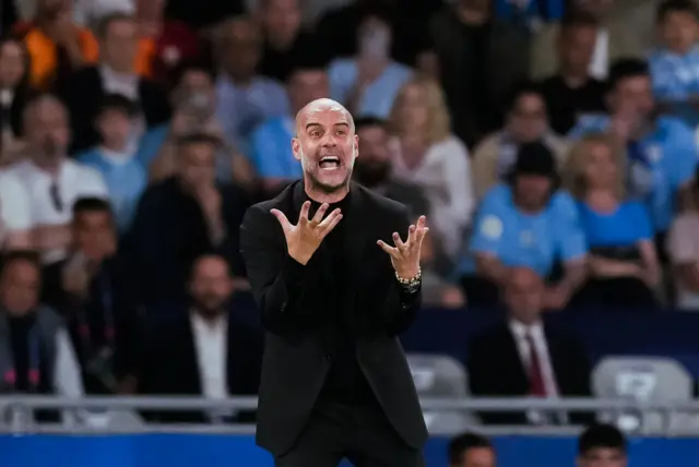 Guardiola holds his hands up in front of him whilst shouting in exasperation.