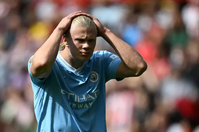 Haaland smoothes back his hair after missing a chance.