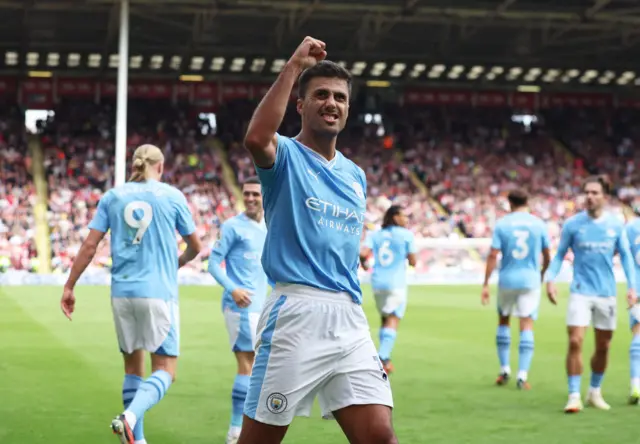 Rodri fist pumps to the travelling fans as his teammates head back to kick off.