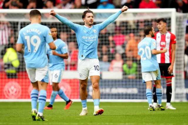 Grealish throws his arms wide in celebration as sheffield united players stand defeated.