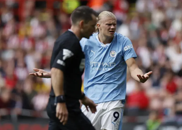 Haaland stands bemused with his arms wide after an argument with the ref.