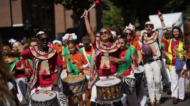 Parade performers beat drums as they march