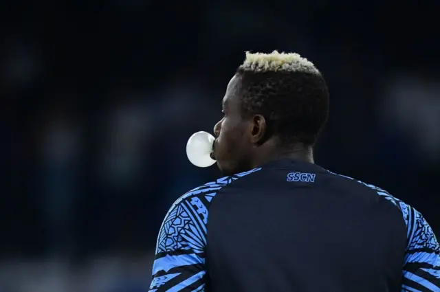 Napoli's Nigerian forward #09 Victor Osimhen makes a bubble with a gum as he stands on the pitch before the Italian Serie A football match Napoli vs Sassuolo on August 27, 2023.