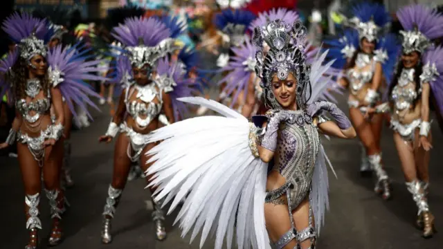 Women in feathered costumes dance in the street