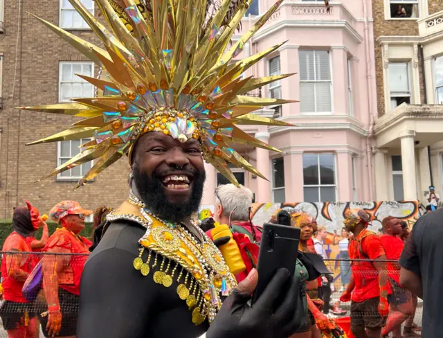 A man in a gold head dress smiles