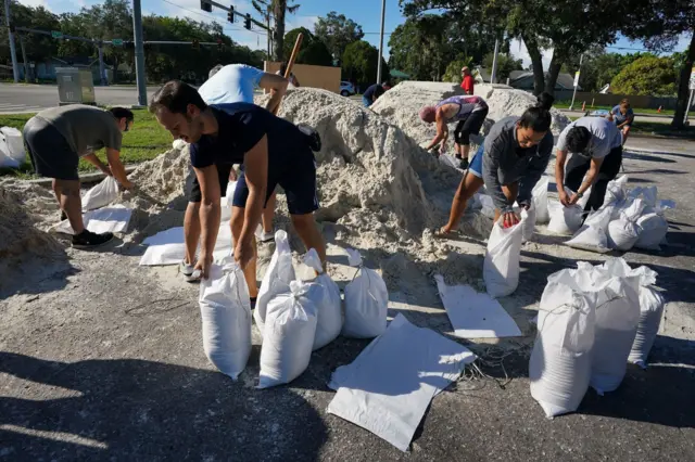 Local residents fill sandbags in preparation for Tropical Storm Idalia, at a self-serve station at Pride Park in Bradenton, Florida