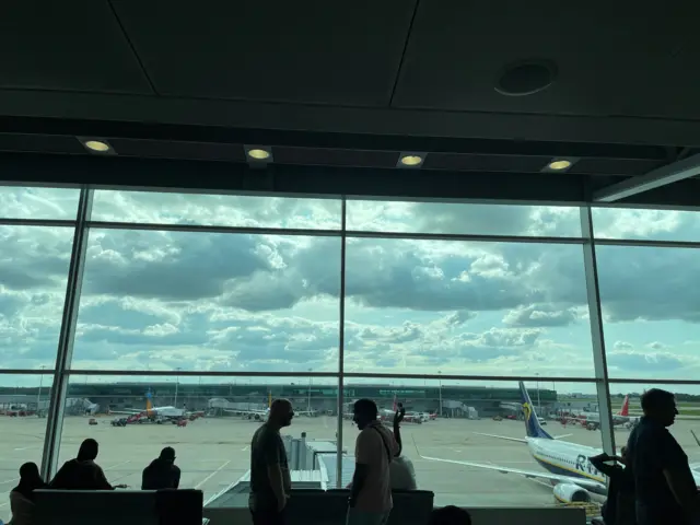 Passengers awaiting news on cancelled or delayed flights at London Stansted Airport gesture as they discuss the situation on Monday, in Stansted, Britain