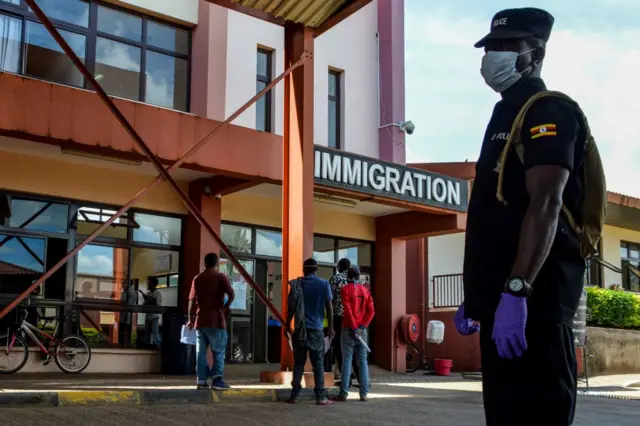 A Ugandan security officer stands guard as truck drivers go through the Uganda's immigration office in Malaba, a city bordering with Kenya, in Uganda, on April 29, 2020. - All truck drivers ferrying goods crossing the border from Kenya must take a test for the COVID-19 by Ugandan health officials and wait 24 hours to get the result. After entering Uganda, the driver must stay inside the truck, only allowed to get off to unload at the destination.