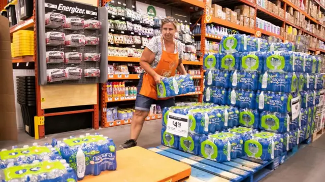 Home Depot employee Sharon Walsh fills a cart with cases of water while moving them to the front door in Ocala