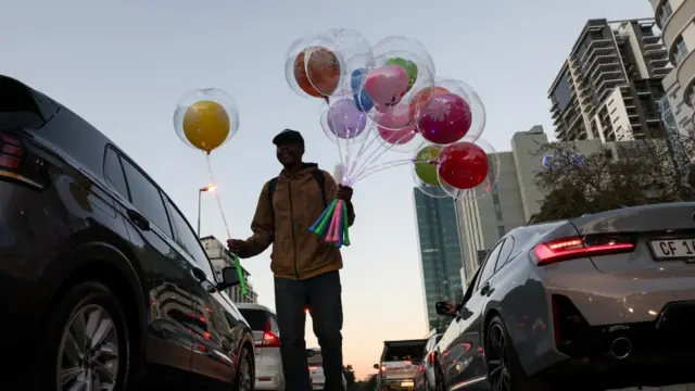 A street vendor sells balloons at a traffic signal along a street in Cape Town, South Africa