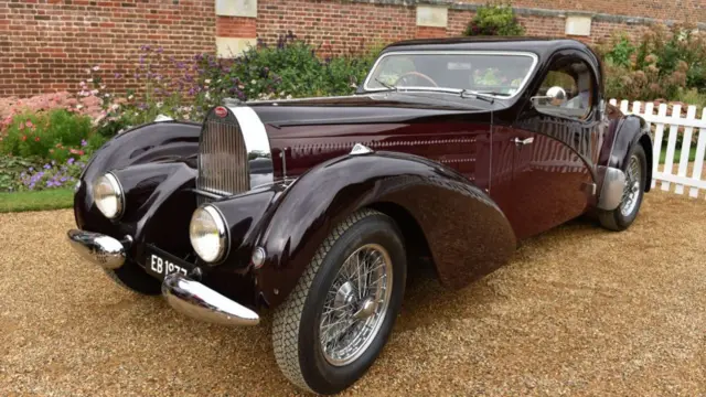 A 1938 Bugatti is parked on a gravel driveway