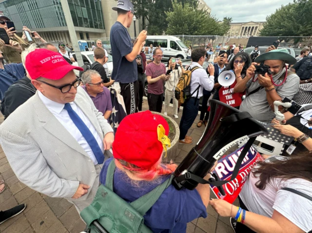 Pro-Trump protesters outside court with megaphones and signs, some are wearing read Keep America Great hats