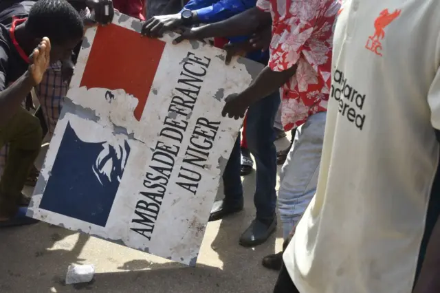 Protesters hold a sign taken from the French Embassy in Niamey during a demonstration that followed a rally in support of Niger's junta in Niamey on July 30, 2023.