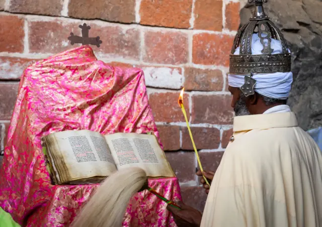 Ethiopian orthodox priest with an old bible in nakuto lab rock church, Amhara Region, Lalibela, Ethiopia on May 2, 2023 in Lalibela, Ethiopia.