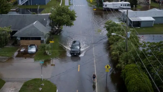 A resident walks along a flooded street in the aftermath of Hurricane Idalia in Hudson, Florida