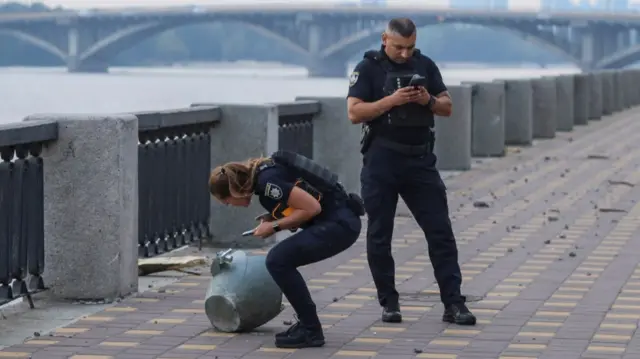 Police officers stand next to a part of a missile which landed on a street during a Russian strike, amid Russia's attack on Ukraine, in Kyiv